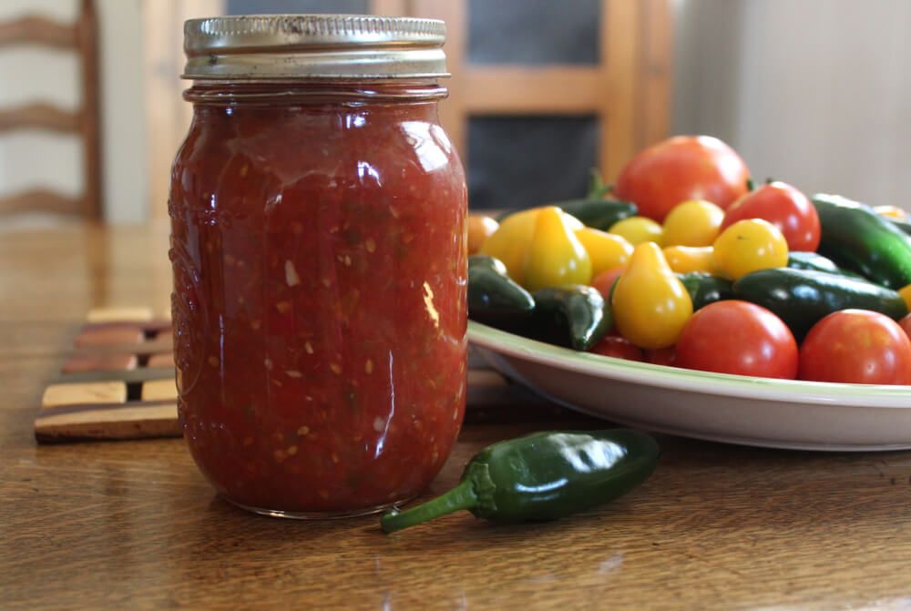canned salsa with tomatoes and peppers in glass jar