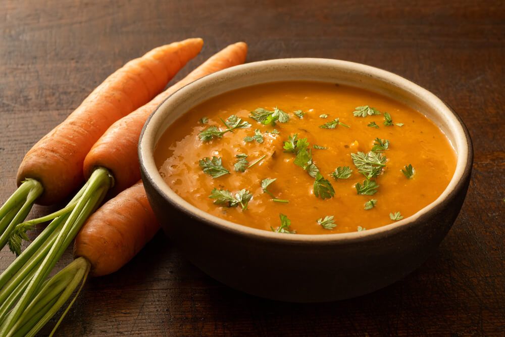 fresh coriander and carrot soup in rustic bowl