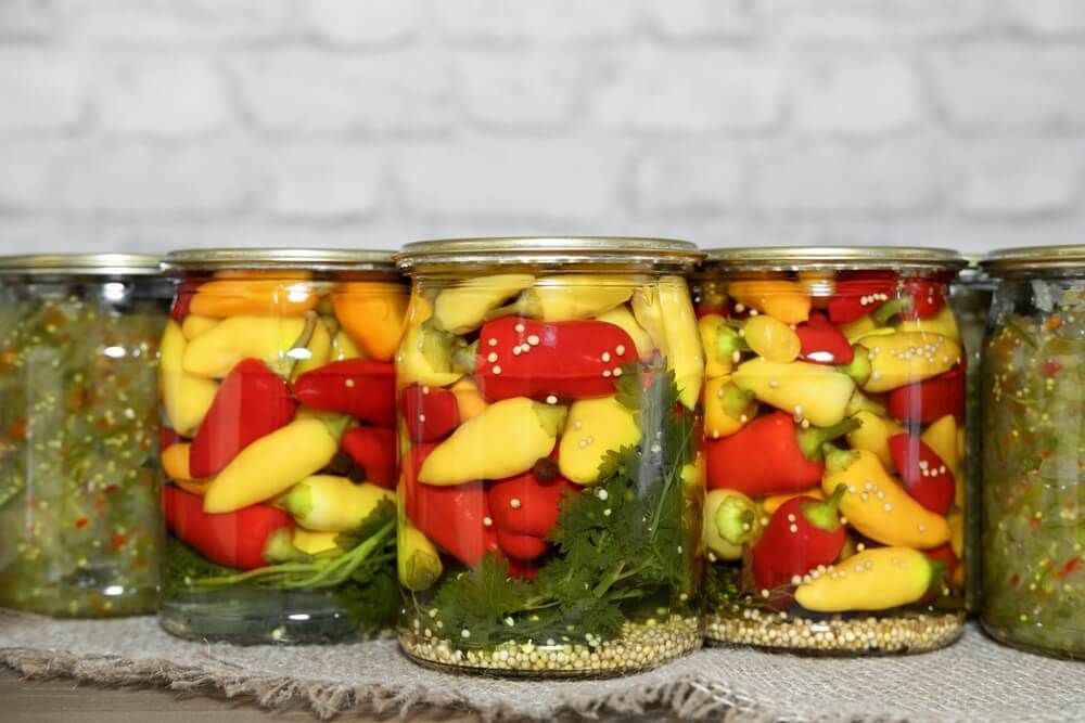 orange red and yellow chili peppers in glass jars