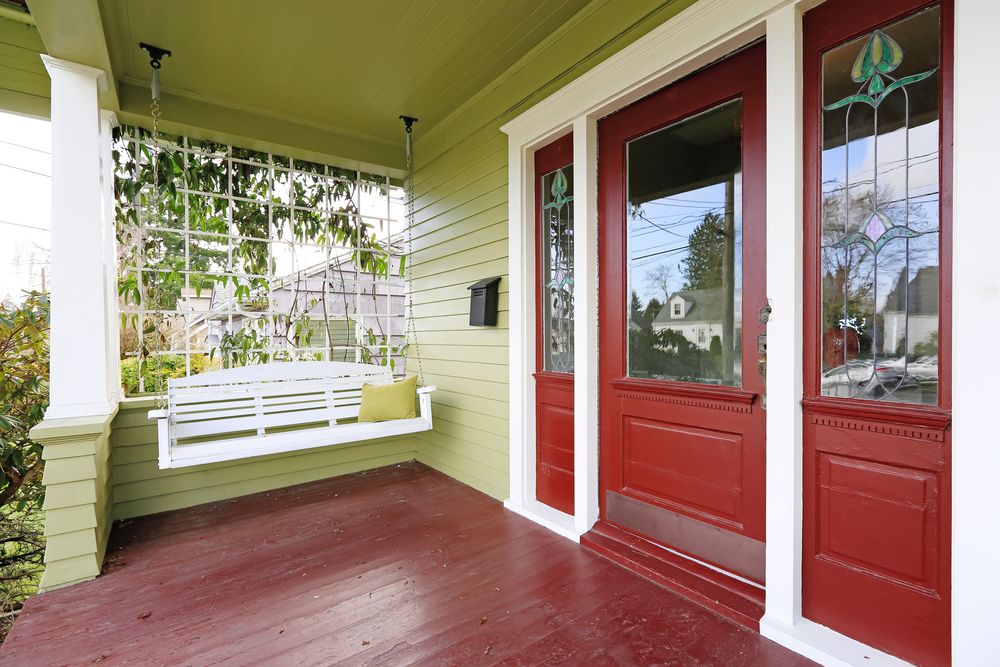 white porch swing beside red door