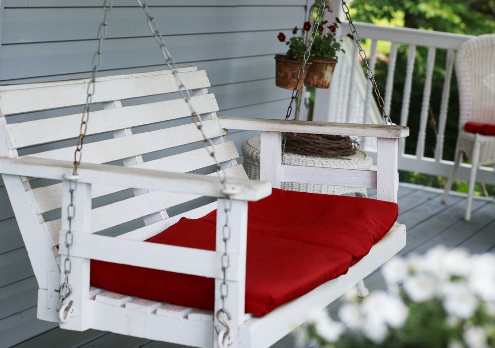 small porch swing with red cushion
