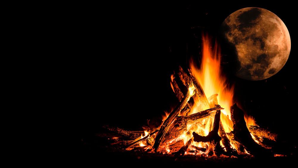 roaring campfire under dark background and full moon
