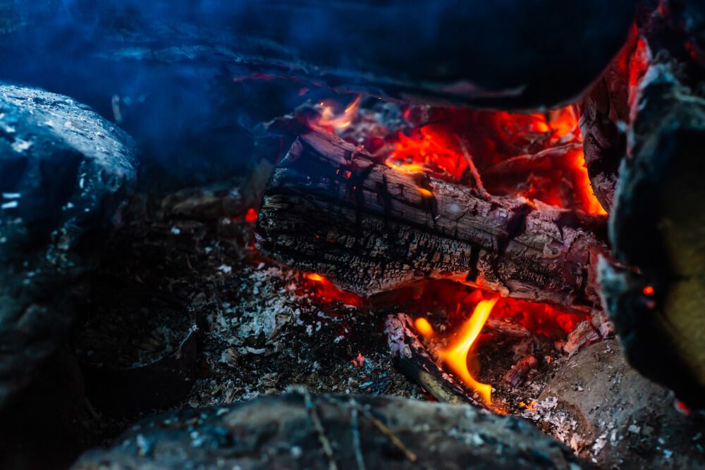 smoldered coals and logs burning in campfire