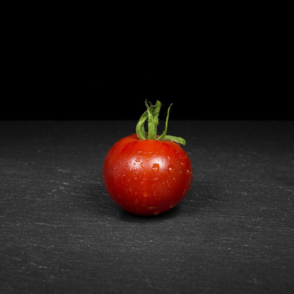stupice tomato positioned on black background