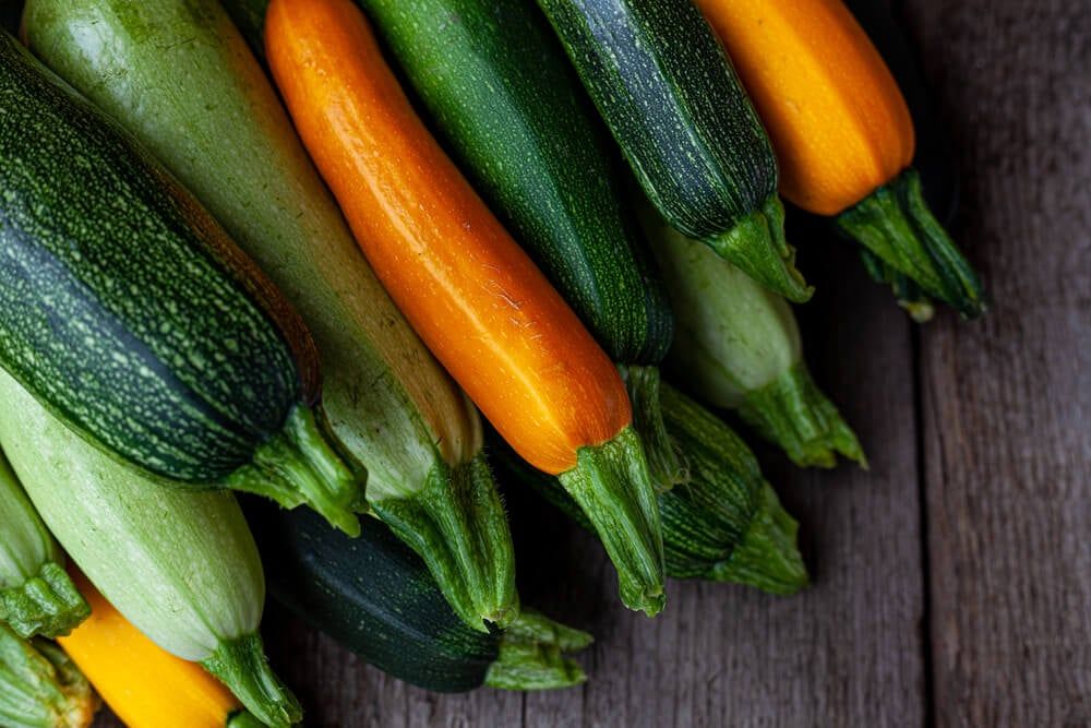 green yellow and orange zucchini on wooden table