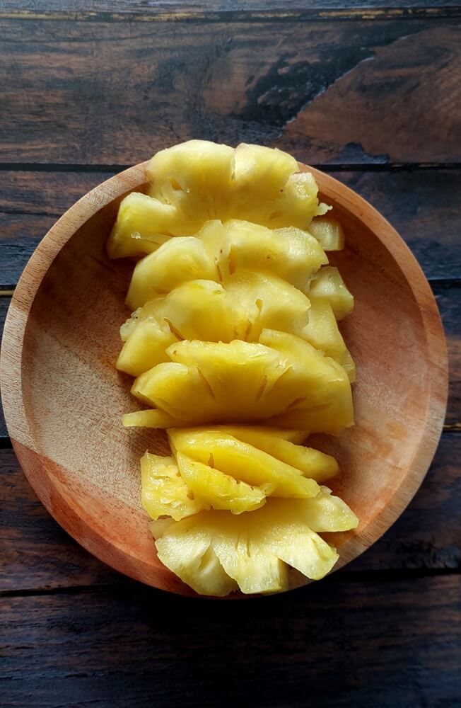 freshly chopped pineapples resting on a wooden plate