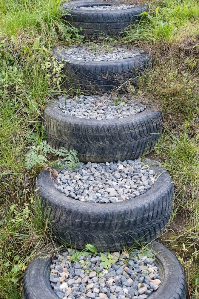 old used car tires stuffed with granite rock to make slope steps in backyard