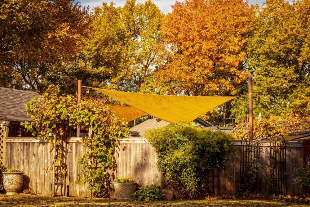 beautiful autumn colors with golden yellow shade sail over enclosed garden