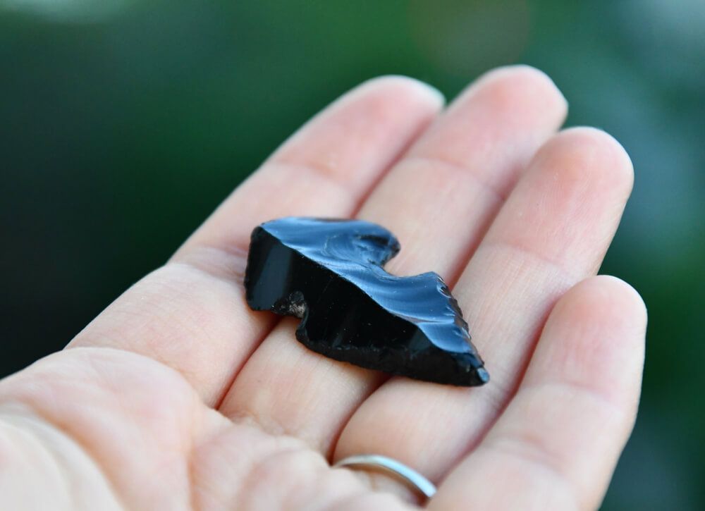 holding a black obsidian arrowhead in hand