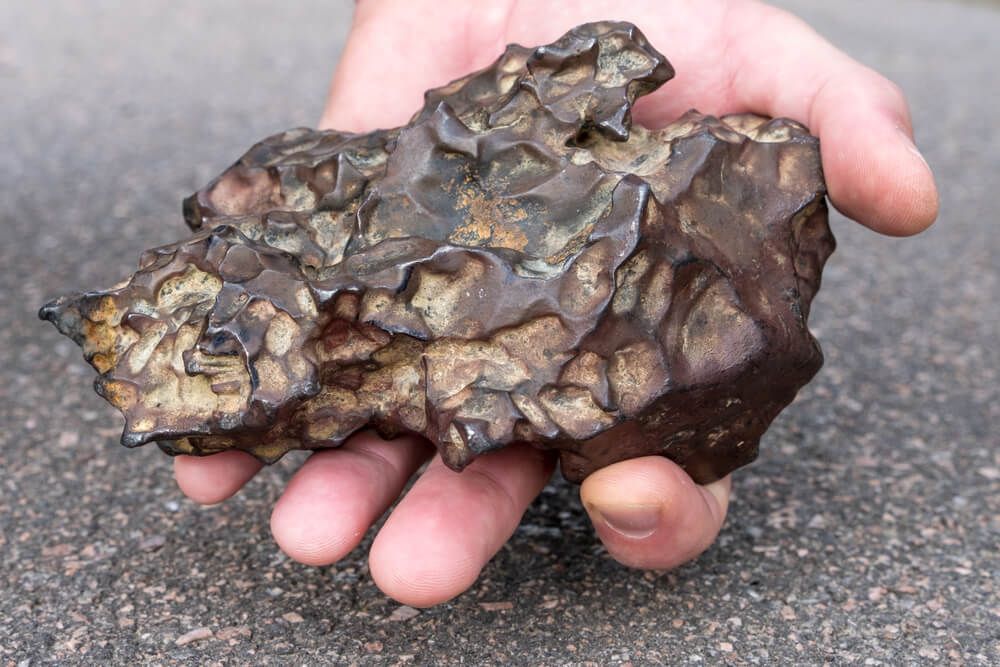 holding massive two kilogram iron meteorite fragment in hand