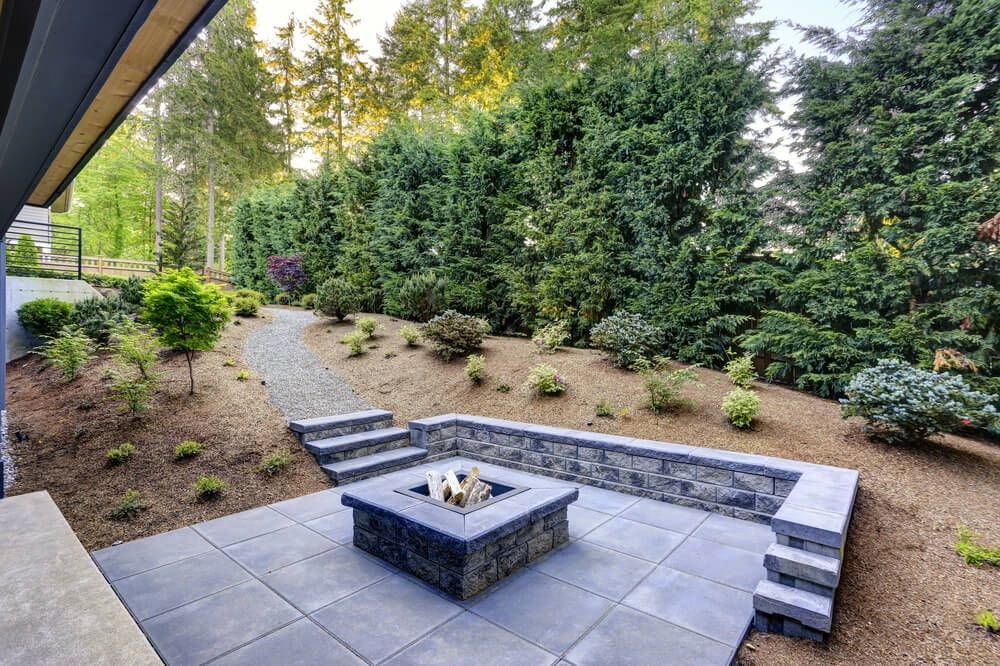 modern backyard patio and rectangular concrete fire pit framed by slate pavers
