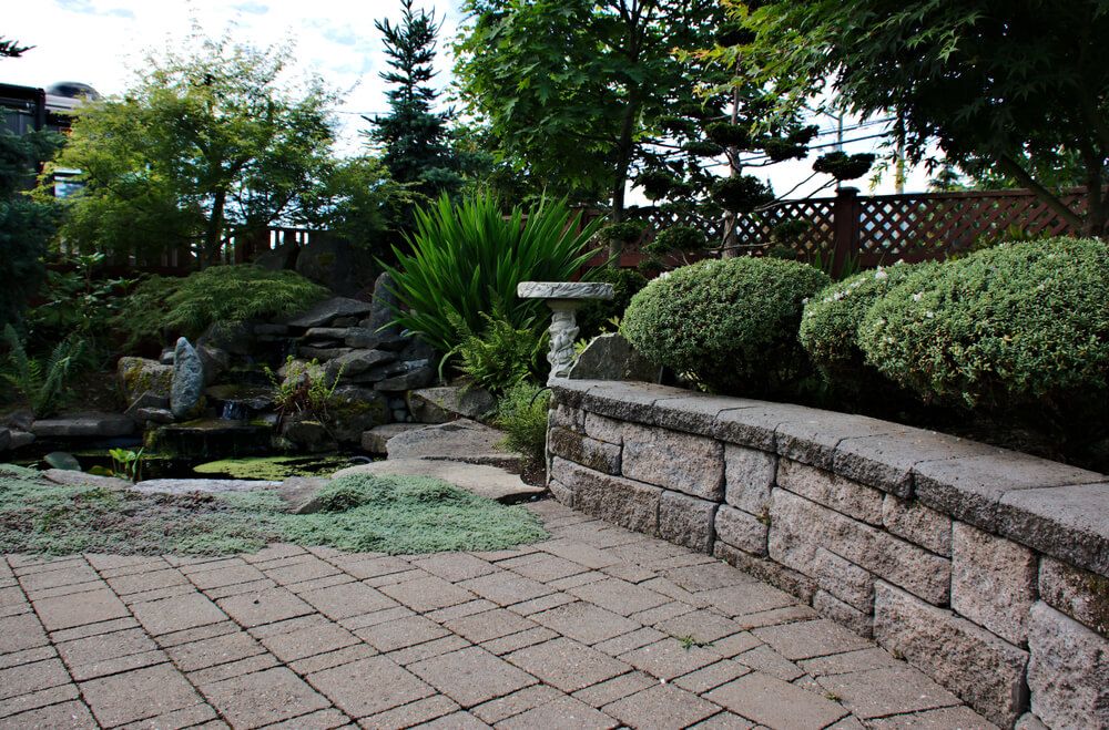 paver deck and block retaining wall with lovely waterfall and pond