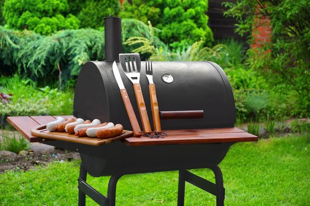 summer bbq preparation with charcoal grill and grilling tools on backyard lawn