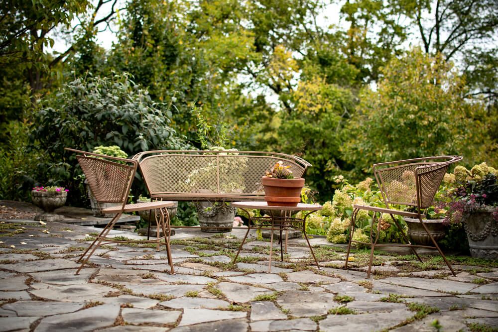 tables and chairs with flagstone pavers surrounded by lush verdure