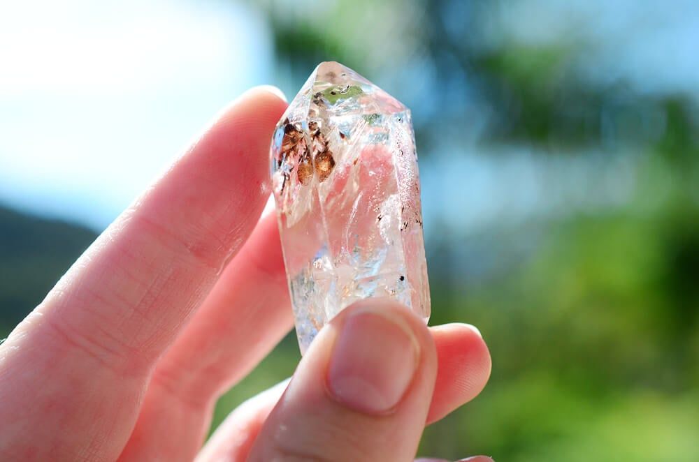 woman holding shiny quartz in hand on a bright sunny day - a valuable rock you can find in your backyard