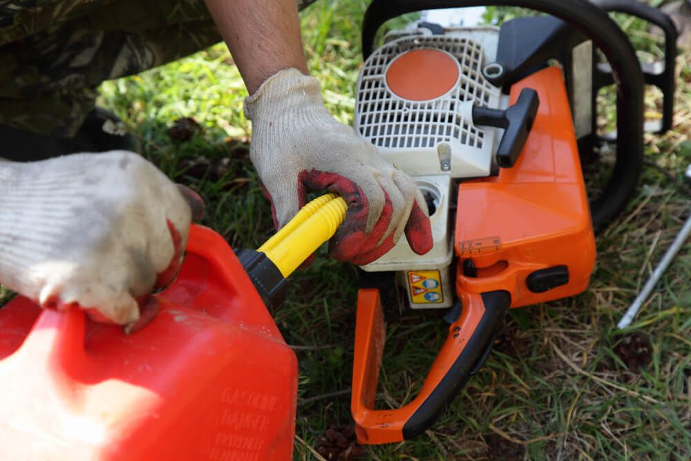 carefully filling chainsaw with gasoline on a summer day
