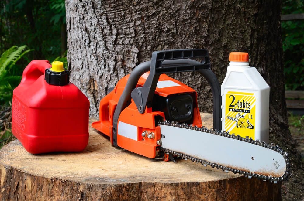 chainsaw motor oil and gasoline cannister resting on a tree stump