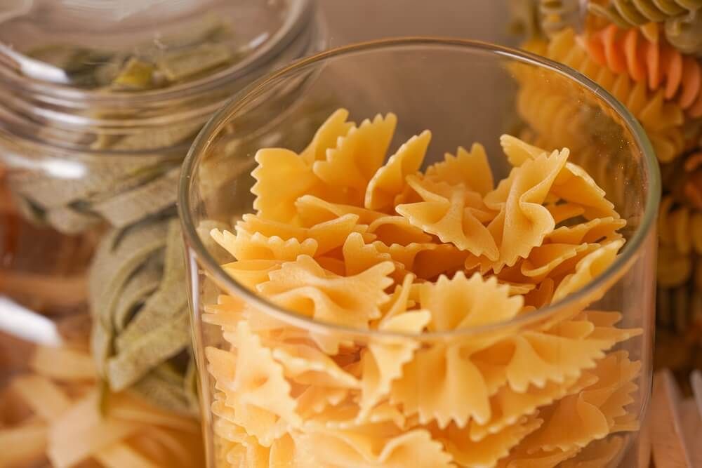 dried pasta in glass jars resting in the kitchen cabinet cupboard