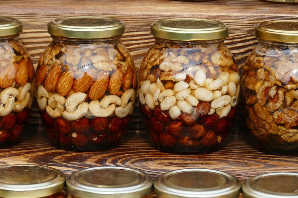 nuts stockpiled in glass jars sitting in pantry cupboard
