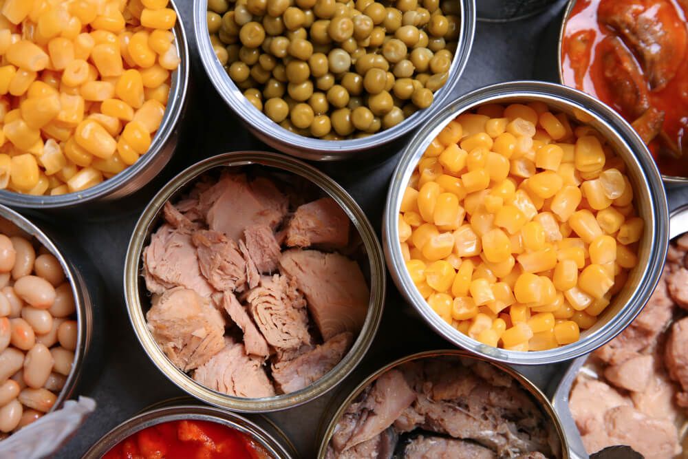 open cans of colorful canned corn peas and meat