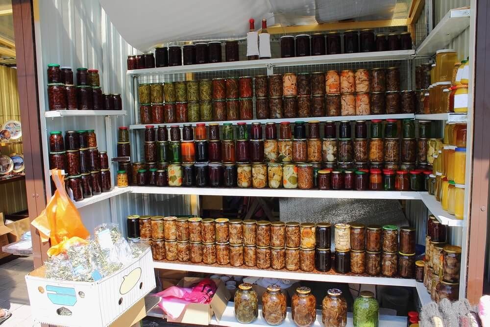 food storage pantry stuffed with glass jars containing preserves fruits veggies and pickled goodies