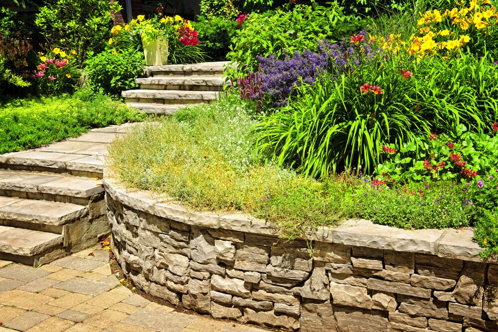 sloped yard landscaping with beautiful colorful garden and a stone retaining wall