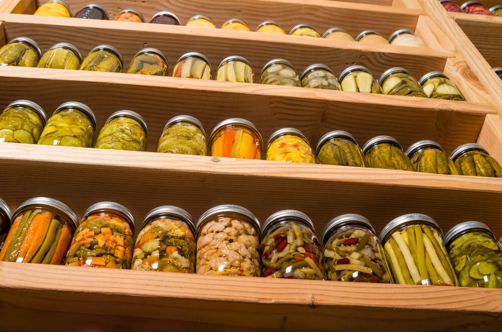 storage pantry stuffed with glass jars containing delicious garden veggies fruits and pickled food