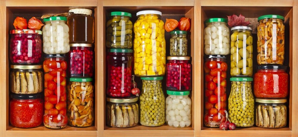 wooden cabinet crammed with many glass jars containing yummy and colorful foods