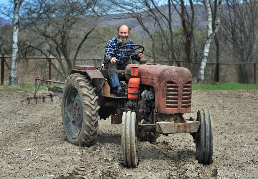 bearded farmer sitting on a nifty tractor