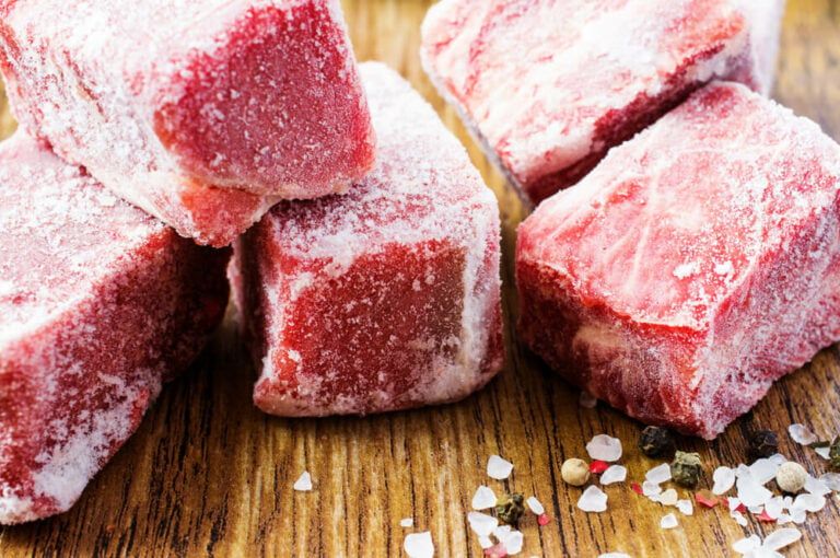 frozen beef chunks resting on a wooden cutting board