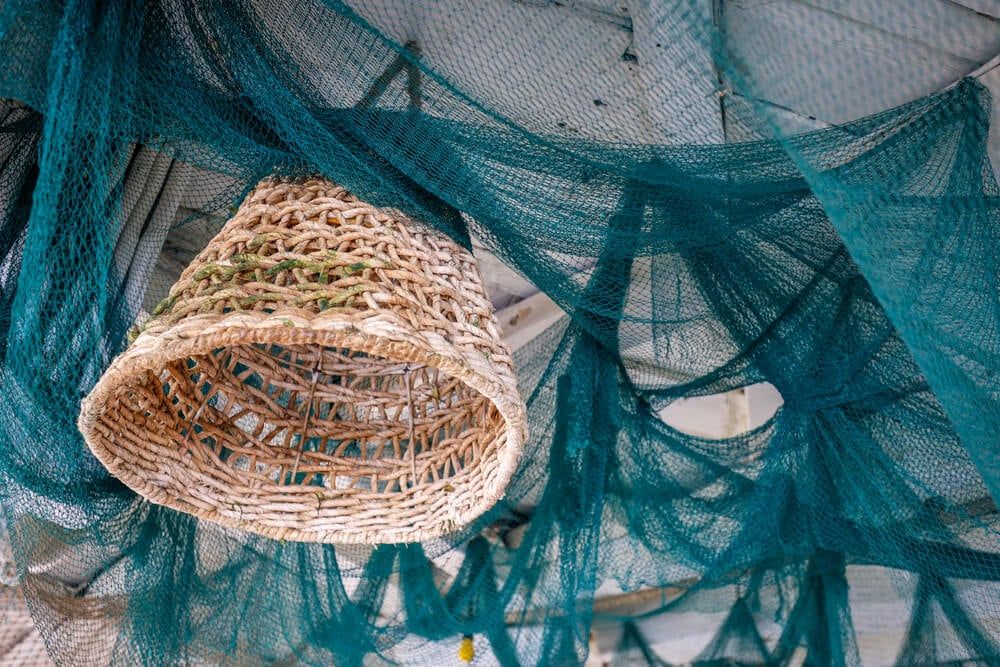 Using an interior boat theme for a porch ceiling with blue fish nets and a wicker chandelier.