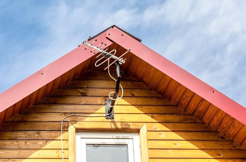 Aerial antenna on the wooden cabin roof for internet and satellite communication.
