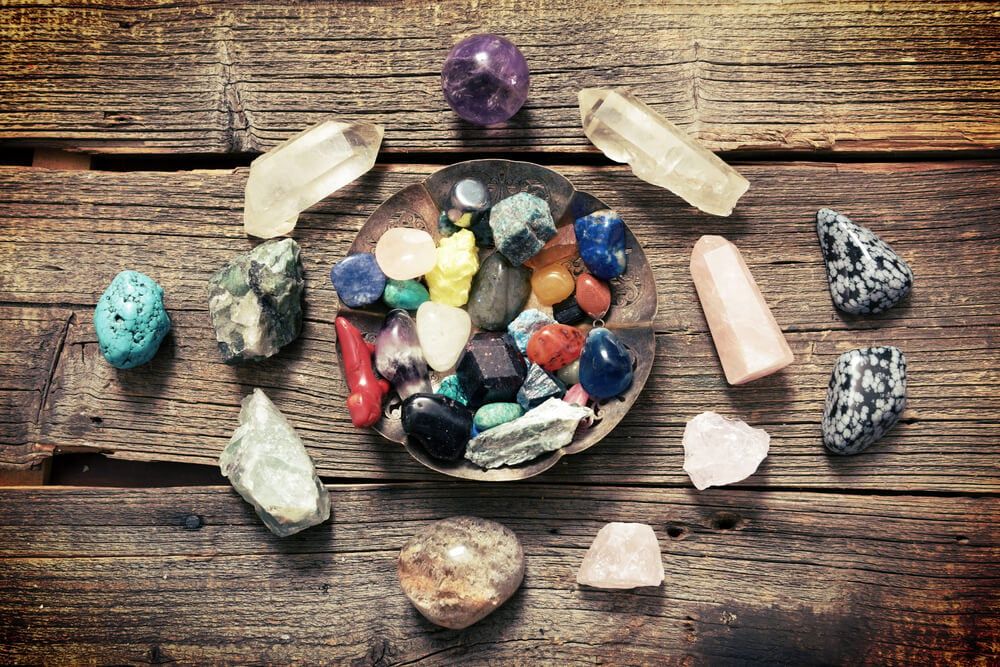 Colorful semi precious gemstones on wooden board including obsidian and rose quartz.